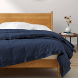 Lightweight navy down blanket with 100% cotton cover and box quilting, featuring contrast piping and breathable comfort for year-round use