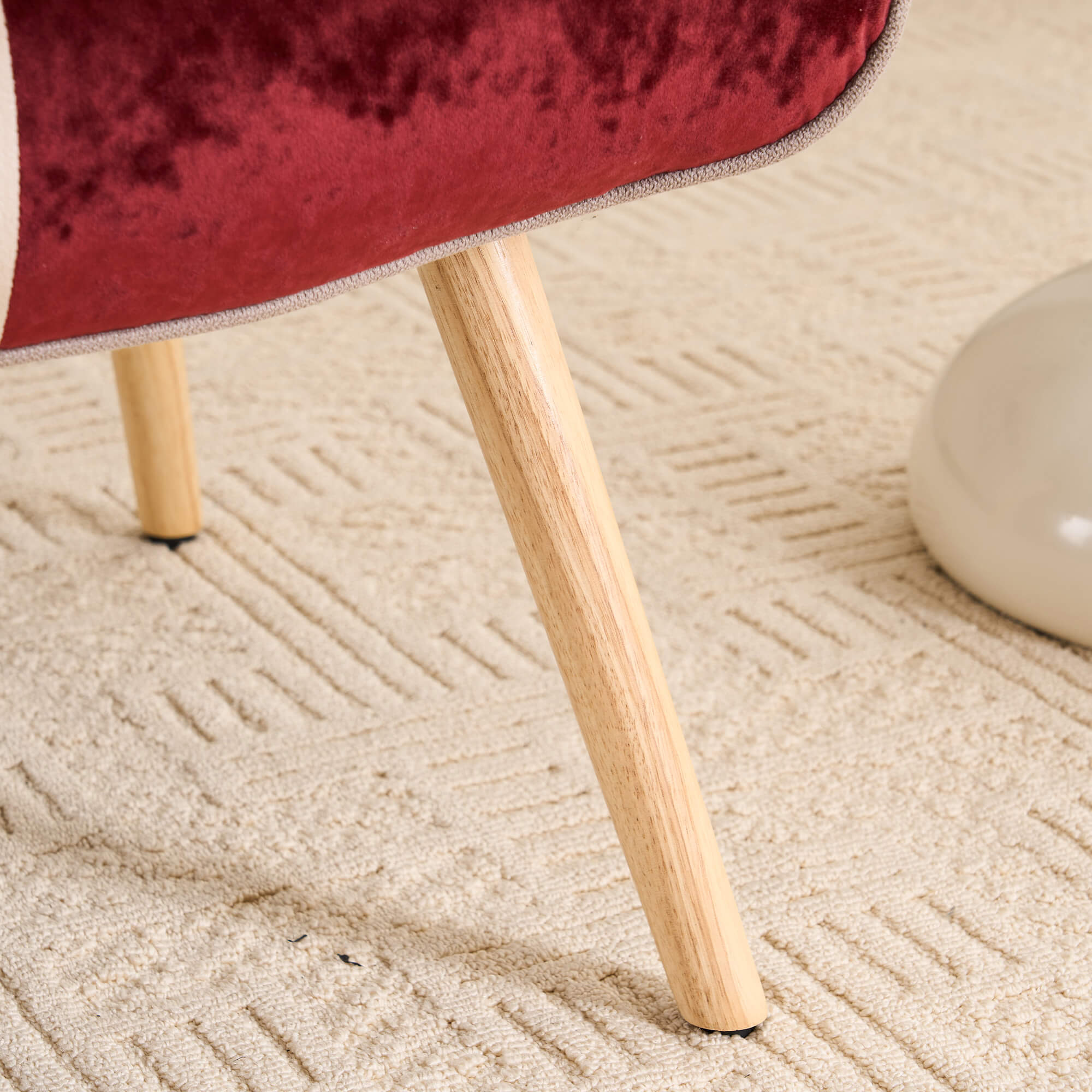 Close-up of solid wood chair leg with natural finish on patchwork accent armchair
