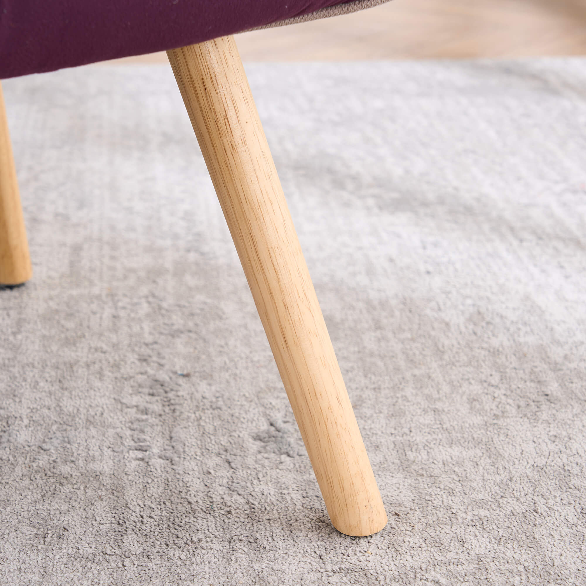 Close-up of solid wood chair leg with natural finish on patchwork accent armchair