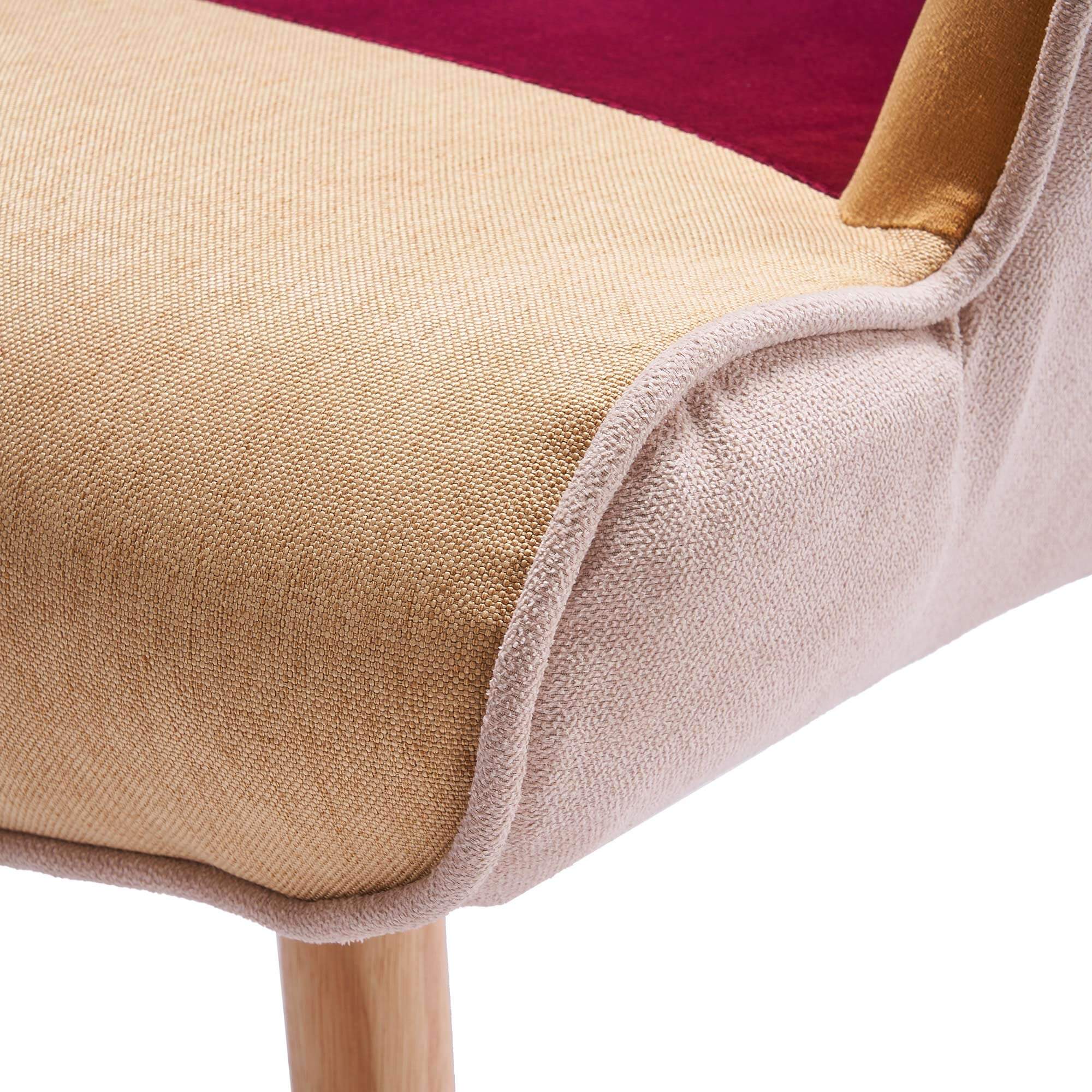Close-up of padded armrest with smooth patchwork fabric upholstery on accent armchair
